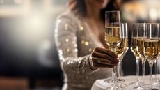 A wedding guest reaches for a glass of champagne on a table.