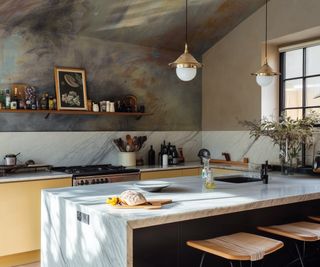 kitchen with large marble clad central island, abstract wallpaper on back wall and extending onto sloped ceiling