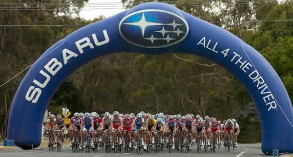 The peloton head under the Subaru archway at the start of the home straight in Buninyong