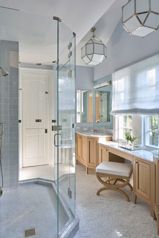 light blue bathroom with timber vanity, glass pendant lights and enclosed shower