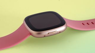 En närbild på boetten och armbandet på en rosa Fitbit Versa 4