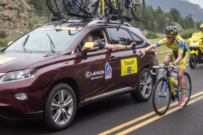 Tinkoff-Saxo's Lars Michaelsen hands off some arm warmers to his rider