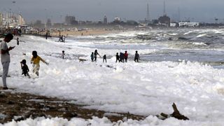 Children play on Marina beach in Chennai, India, which is blanketed in sea foam, Dec.1, 2019.