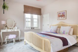 a large rattan bed in a white master bedroom with a traditional dressing table