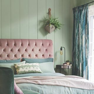 A green-painted bedroom with a pink bed and a panelled wall