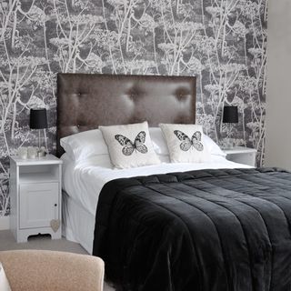 guest room with bed with cushions and wallpaper