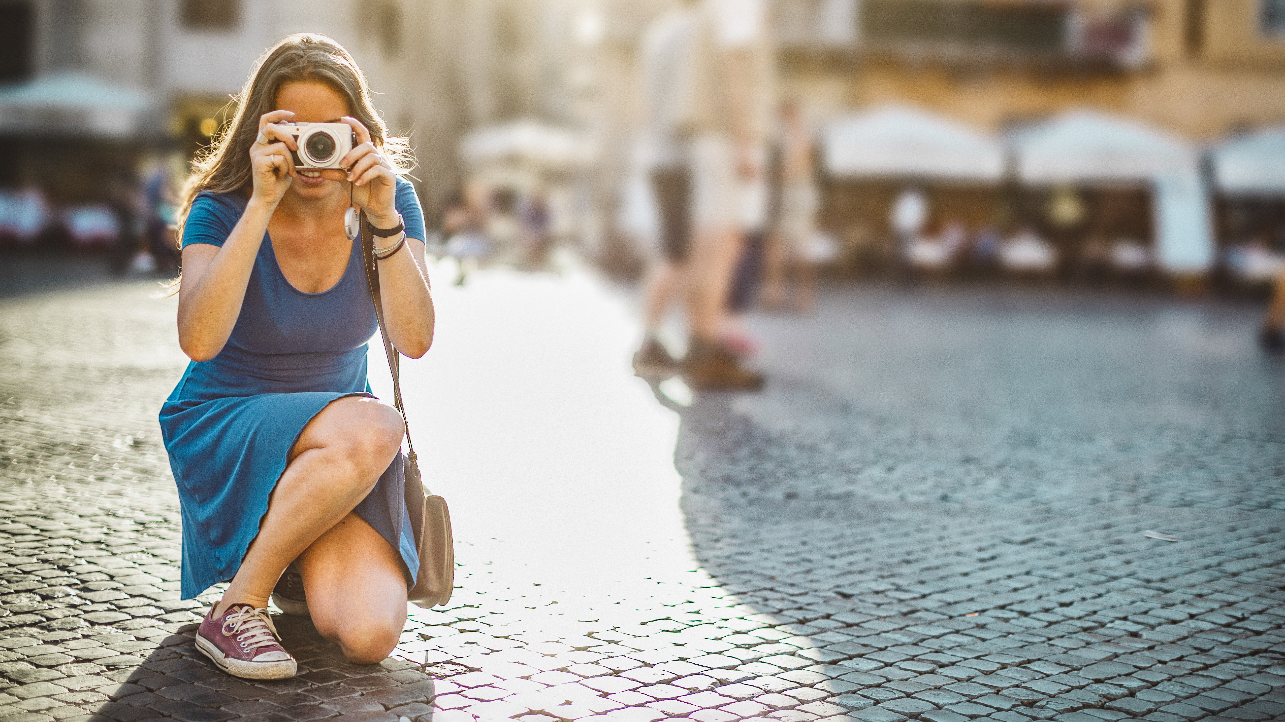 Lone tourist woman kneeling down with compact camera in Rome
