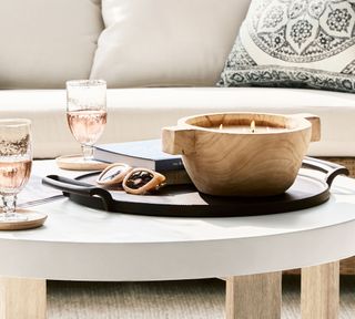 A wooden four wick candle on a coffee table