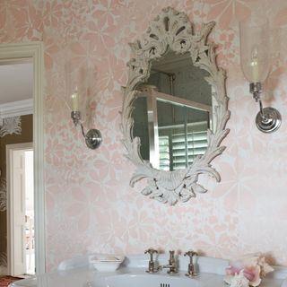 Guest bathroom with mirror on wall and pink foliage wallpaper