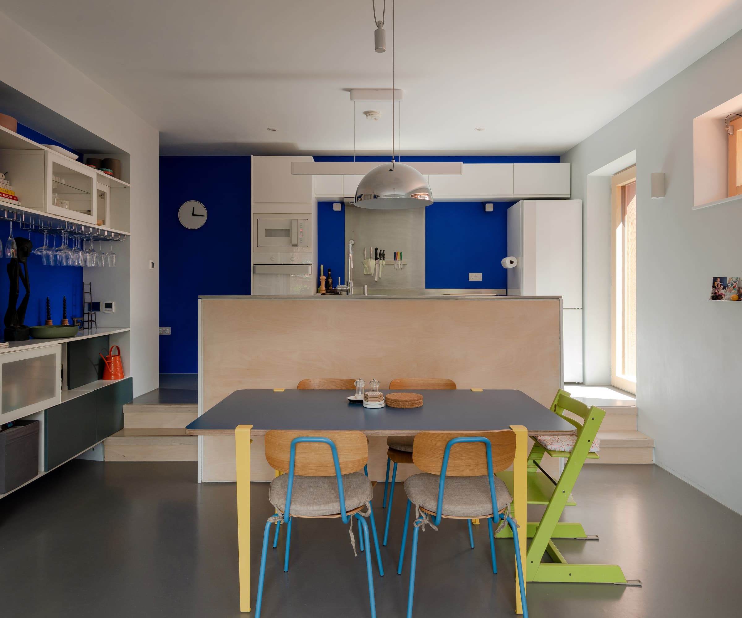 A kitchen with blue walls and grey floors and a porcelain kitchen island