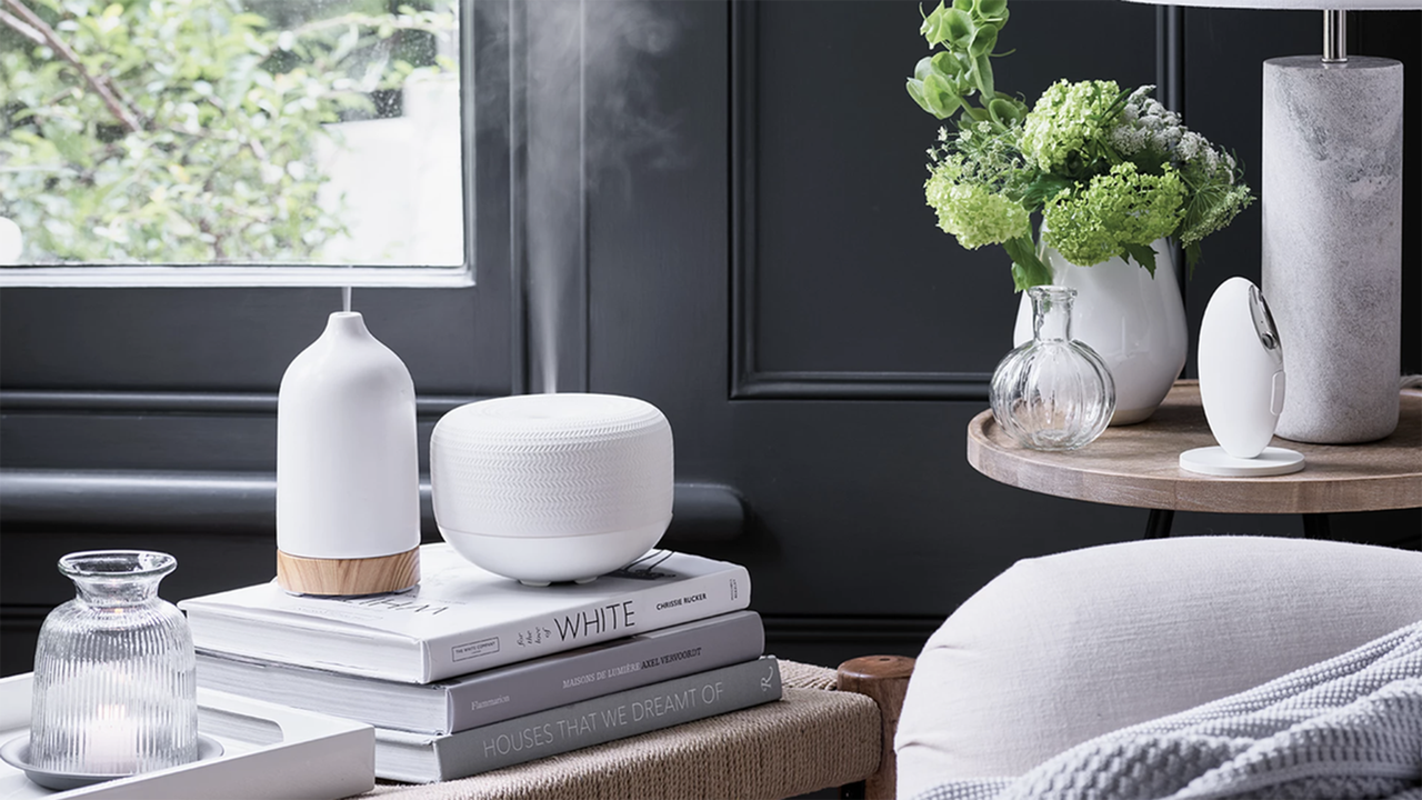 An electronic essential oil diffuser positioned on top of hardback coffee table books