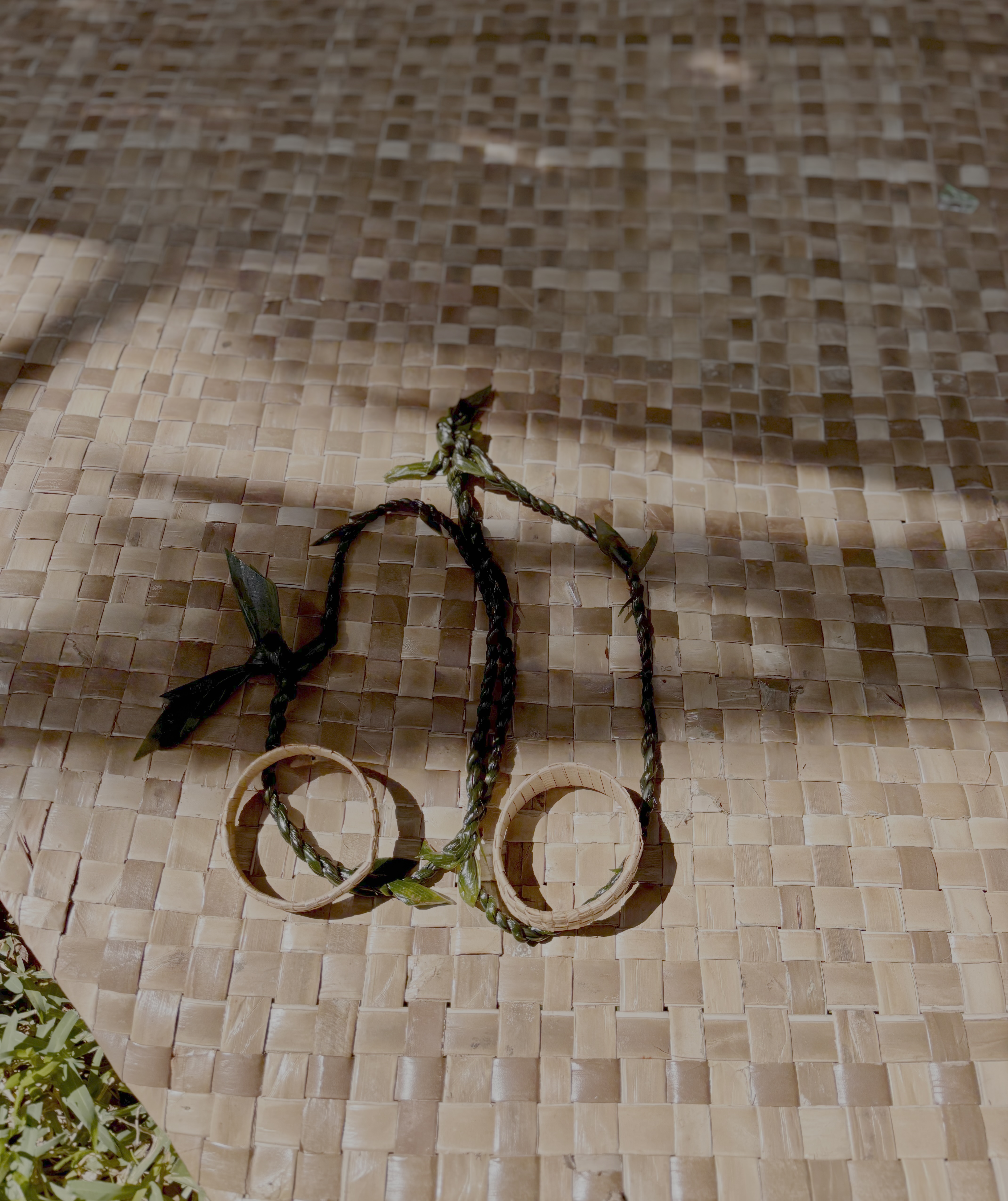 Handmade leis from a Hawaiian lei-making class resting on a woven mat.