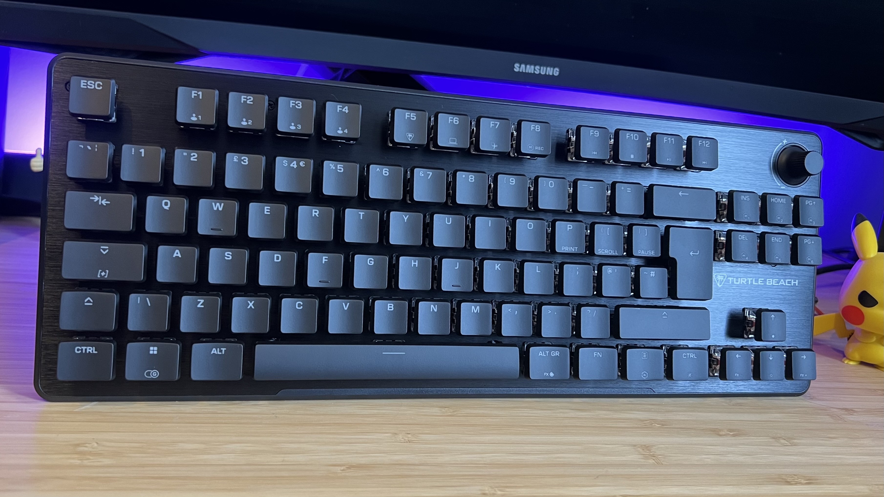 Turtle Beach Vulcan II TKL gaming keyboard on a wooden desk with purple backlighting