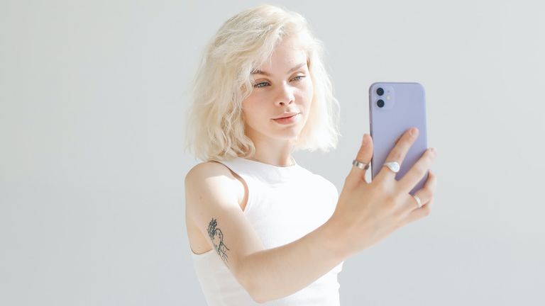 Woman with white hair using iPhone to take photo