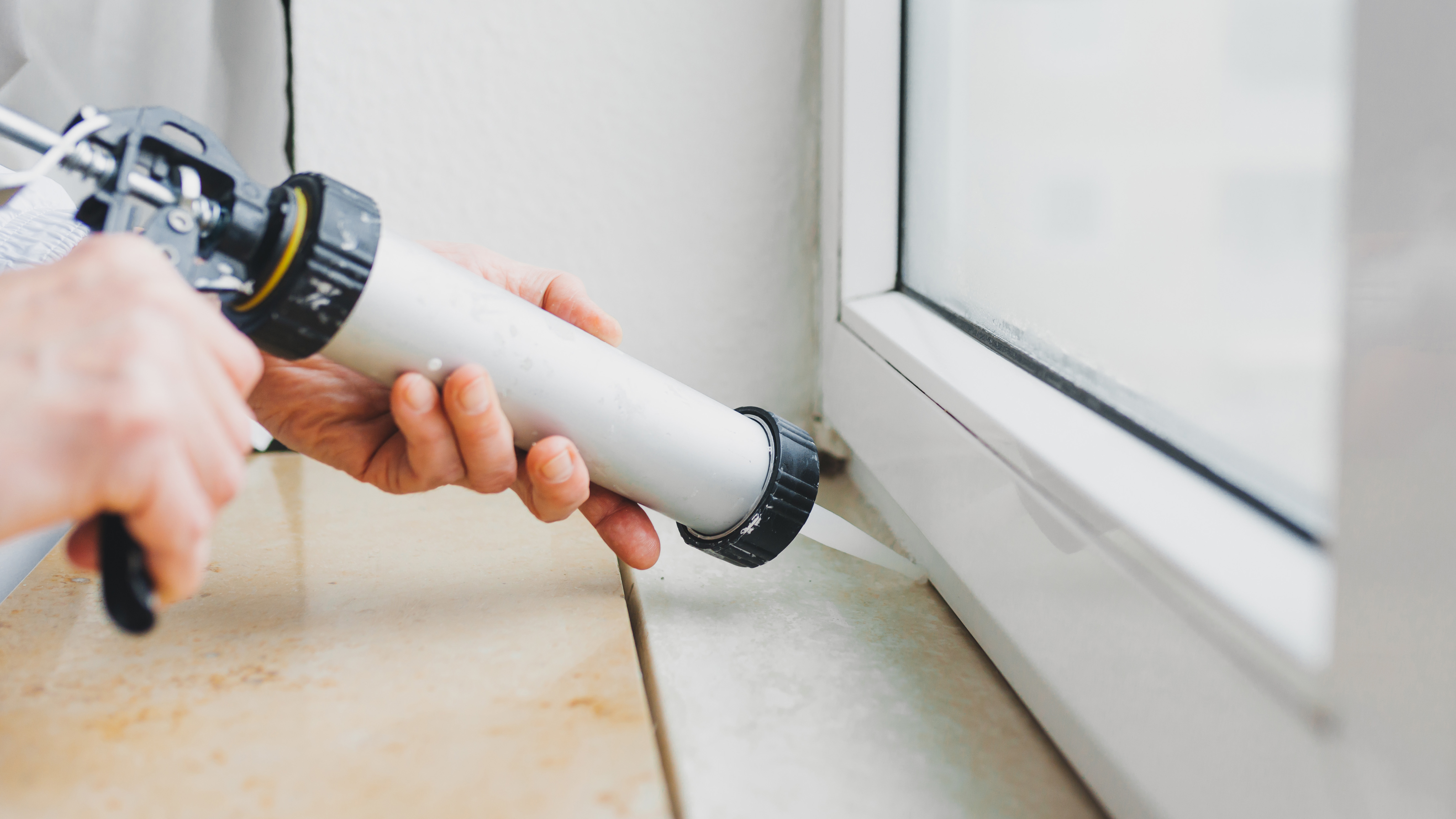 Sealing window base with caulking gun