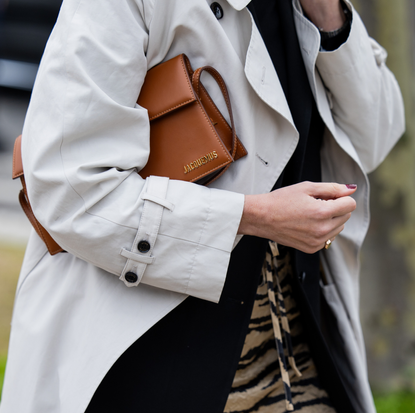 A guest wears grey coat, brown Jacquemus bag, skirt with animal print outside Balenciaga during the Womenswear Fall/Winter 2024/2025 as part of Paris Fashion Week on March 03, 2024 in Paris, France.