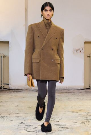 a photo showing the fall jacket trend, hourglass blazers on the Carven runway with a model wearing a brown turtleneck with a tailored brown blazer, gray skinny trousers, black furry heels and a clutch bag