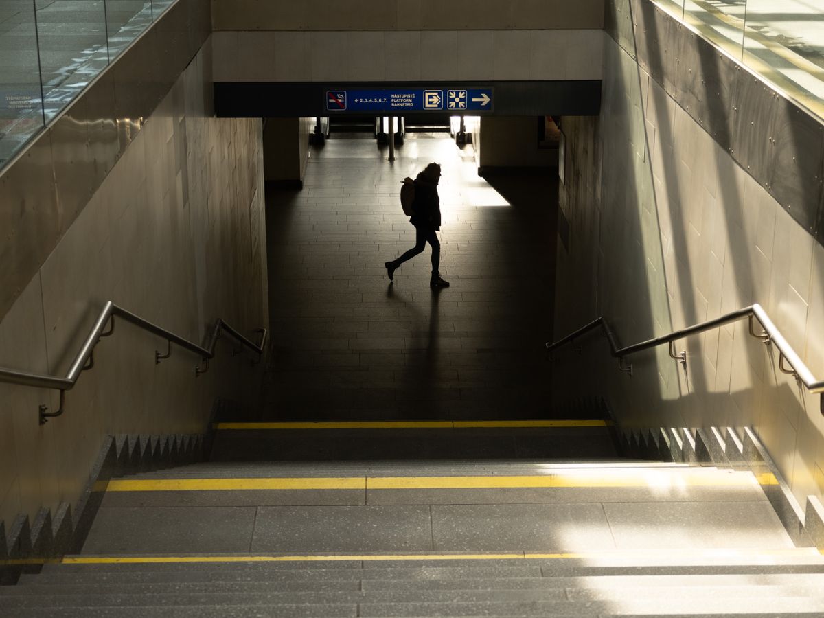 Stairway in a train station with a person walking across the bottom silhouetted by the sun