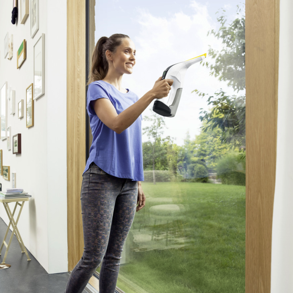 Woman using the Window Vac WV 6 Plus N, one of the best window vacs, on a giant floor to ceiling window