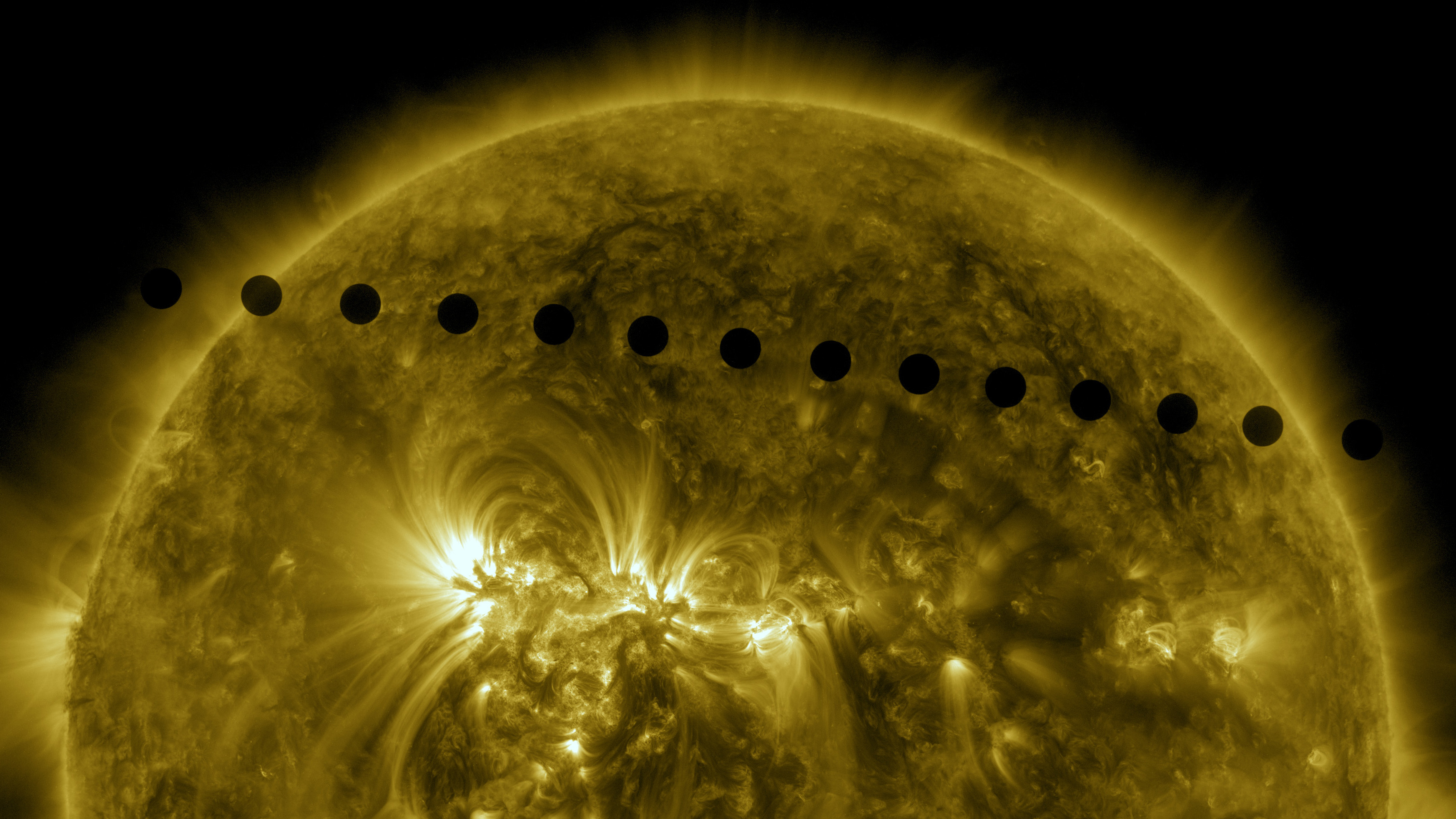 A sequence of black circles cross the face of the sun.