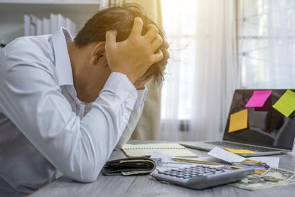 Man sitting at desk with his head in his hands