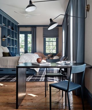 Close up of white desk area in bedroom, white metal storage locker beside desk area, white desk chair with fur seat cushion, desk and locker decorated with small storage trays and pots, high shelf decorated with books and plants