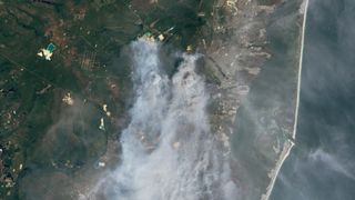 smoke emanating from a large wildfire is seen spreading for miles as imaged by a satellite in Earth orbit