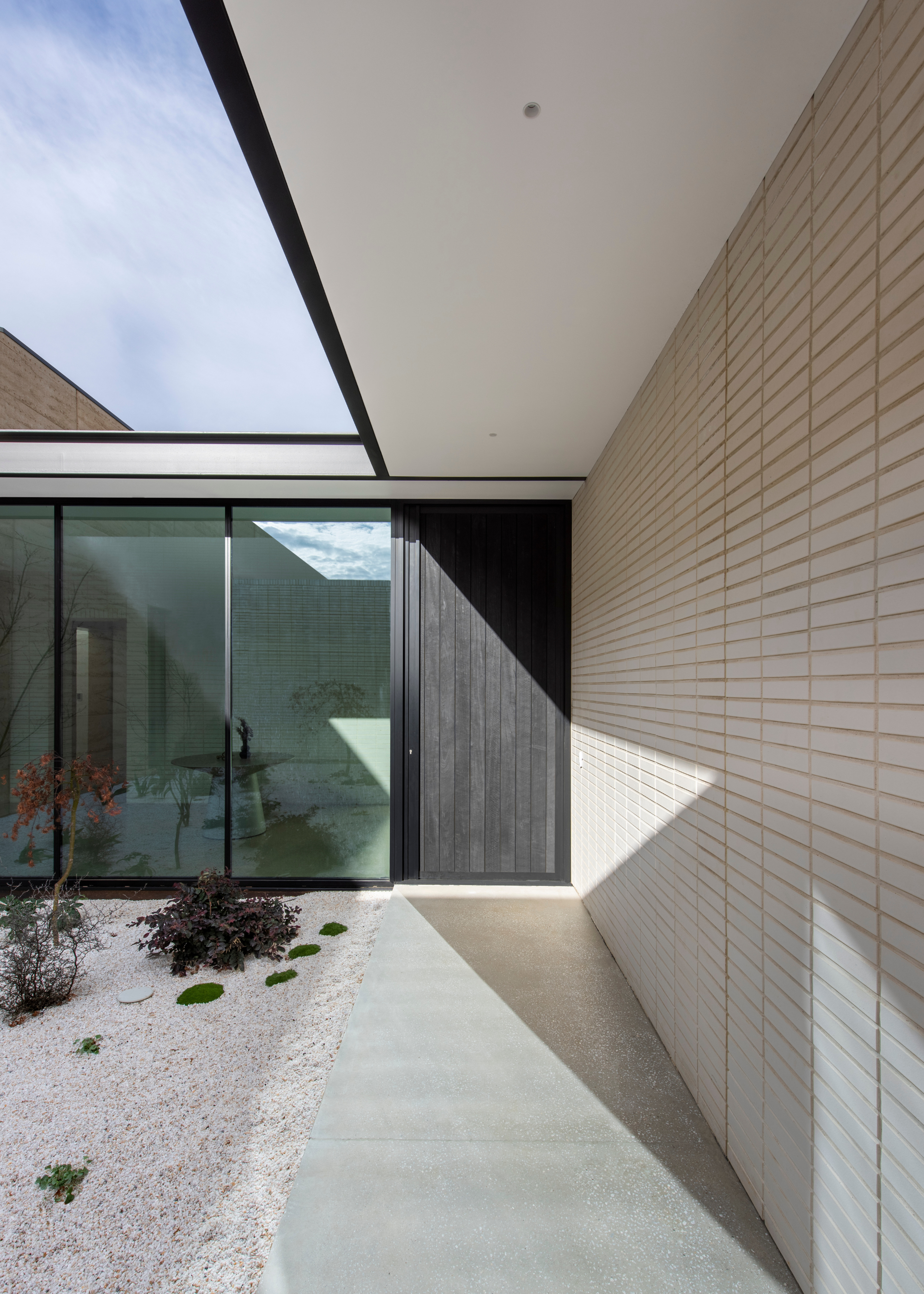 A paved walkway leading to a black wooden door