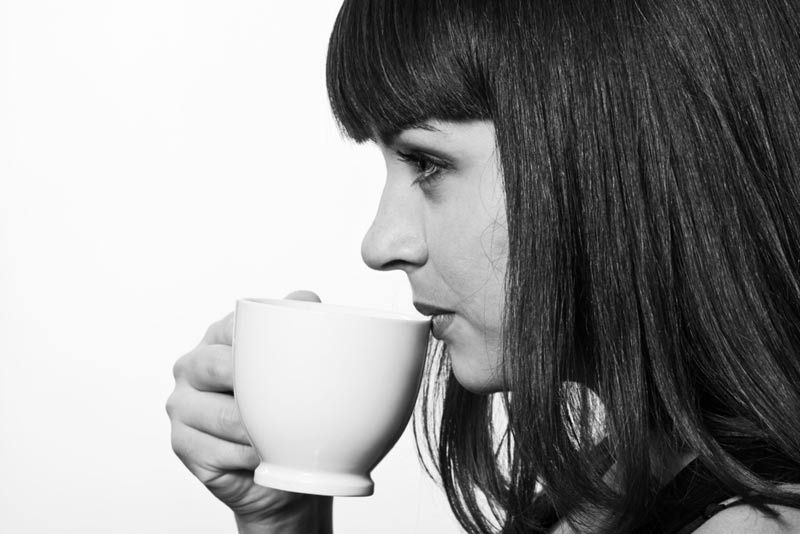 Profile portrait of young woman drinking a cup of coffee, in monochrome.