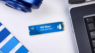 A Western Digital Blue SA510 SATA SSD placed on a desk next to a laptop