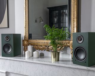 Triangle speakers shown on top of a fireplace mantel