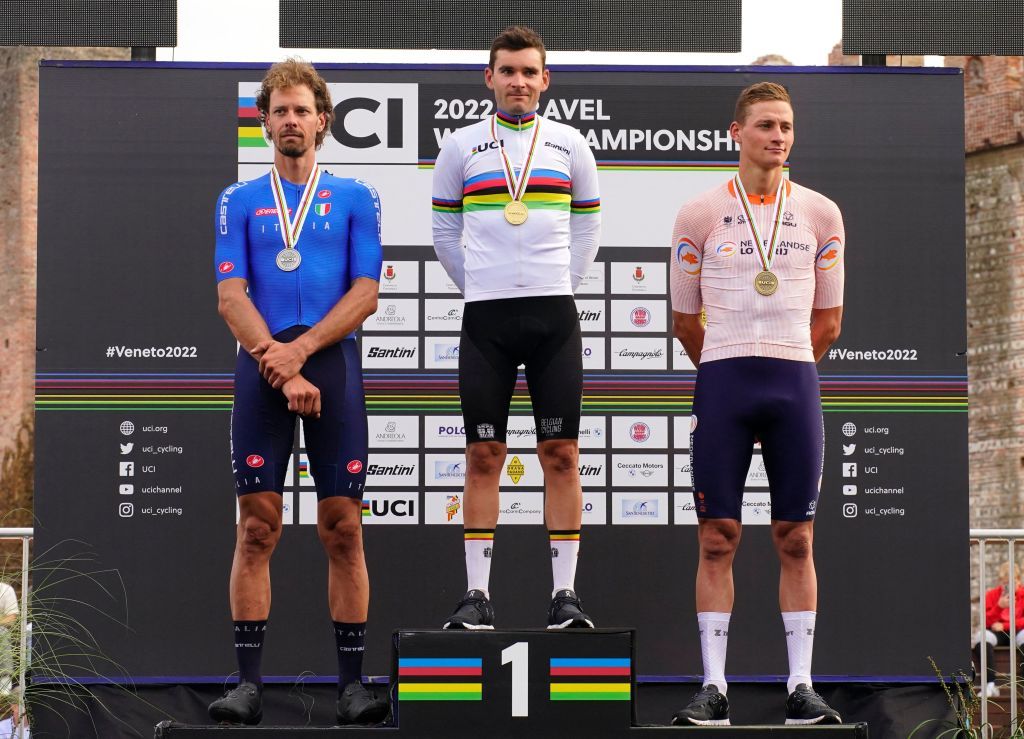 Gianni Vermeersch in the rainbow jersey flanked by Daniel Oss and Mathieu van der Poel on the UCI Gravel World Championships 2022 podium