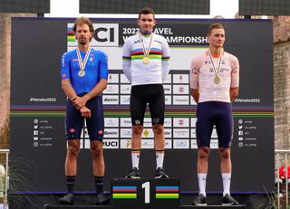 Gianni Vermeersch in the rainbow jersey flanked by Daniel Oss and Mathieu van der Poel on the UCI Gravel World Championships 2022 podium