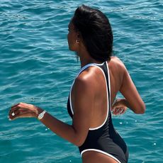 Woman wearing black and white one-piece bathingsuit on background of blue water.
