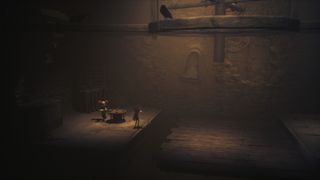Little Nightmares 3 screenshot showing a dimly lit barn room. Two tiny characters stand looking up towards wooden beams