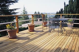 Outdoor decking with plants and a table and chairs.