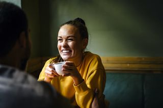 woman smiling while holding coffee cup