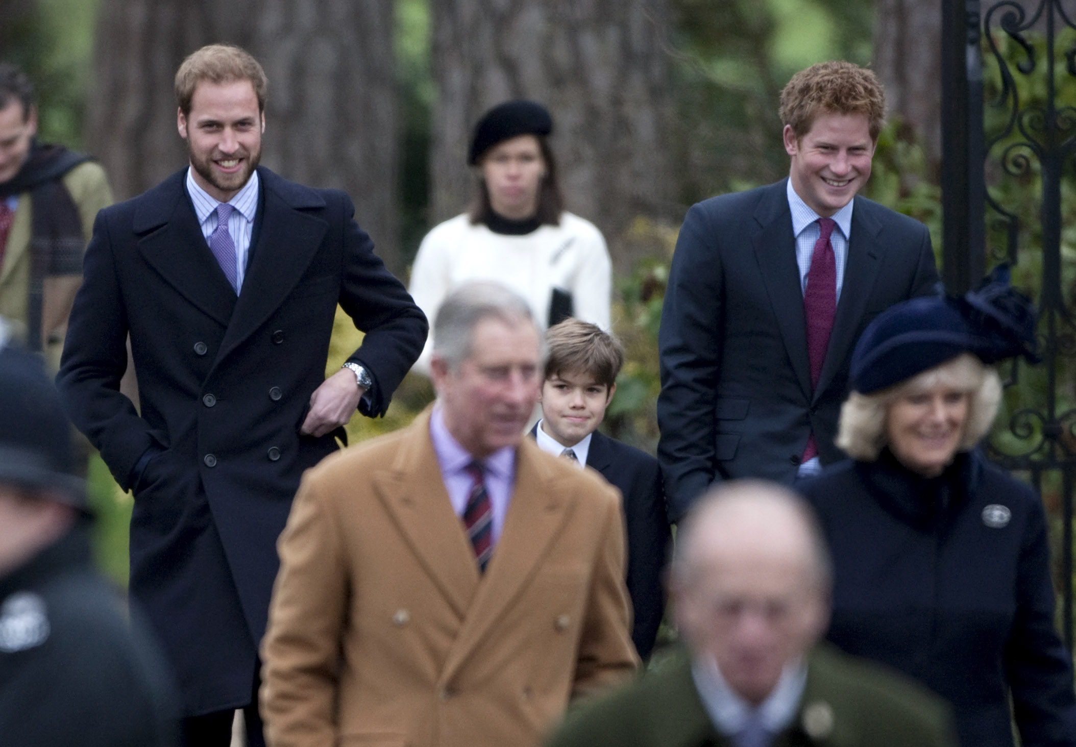 Prince William and Prince Harry wearing coats and ties walking behind The King and Queen at Christmas 2008