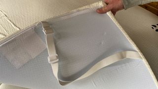 A hand holding the corner of the Panda Bamboo Mattress Topper to show its non-slip underside