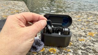 A hand takes a transmitter mic out of the plastic carry case