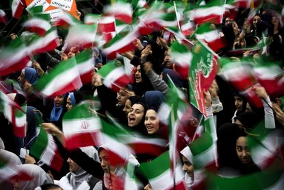 Iranian schoolgirls wave flags at a rally