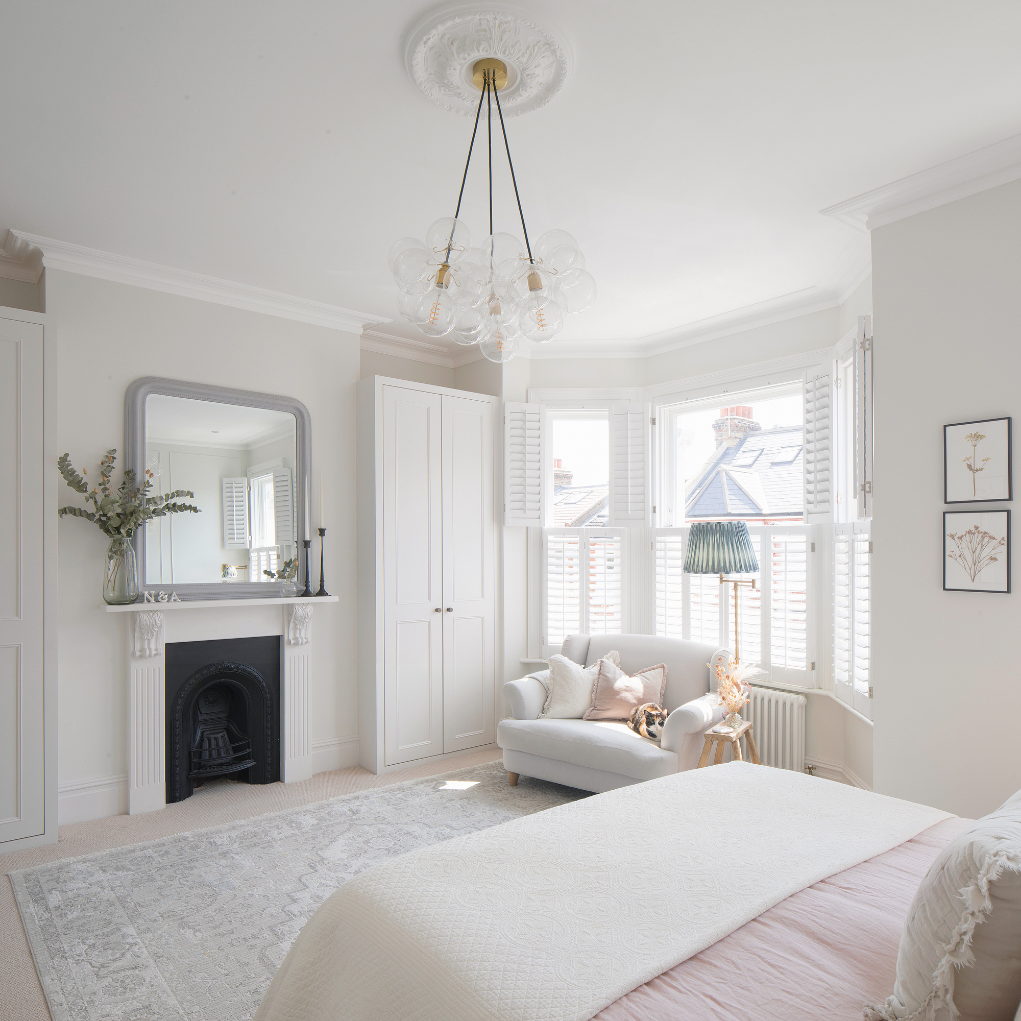 white bedroom with pink bedding large mirror and glass pendant shade