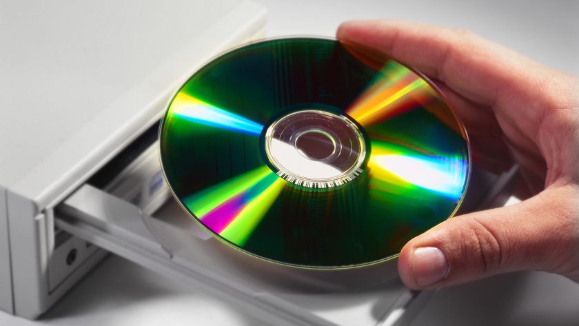 Close-up of a hand inserting a compact disc into a drive 