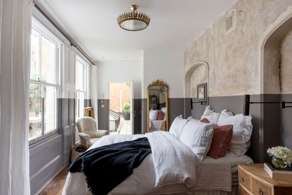 a bedroom with a raw plaster accent wall