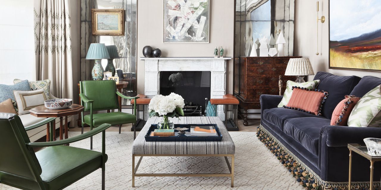 Formal living room ideas with a blue velvet sofa, antique dresser, fireplace with tarnished mirrors either side and green armchairs