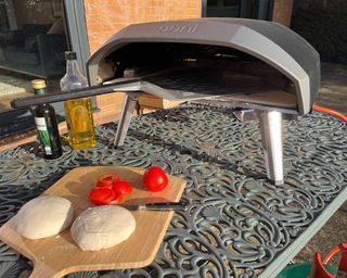 pizza oven on a garden table with pizza dough on a board