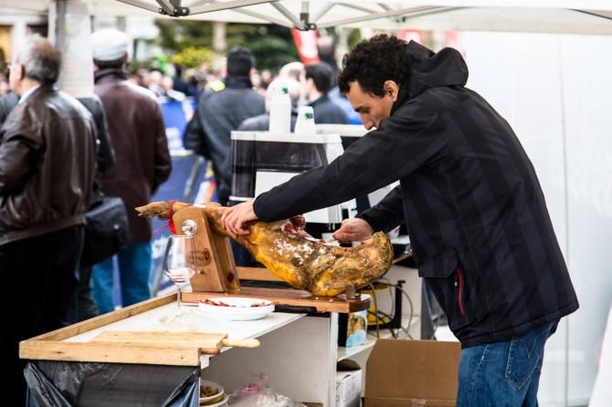 A local vendor cuts fresh ham at the finish line of stage 1 at the Vuelta a Castilla y Leon