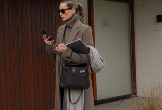 Woman wearing a long brown coat with a matching brown turtleneck sweater.