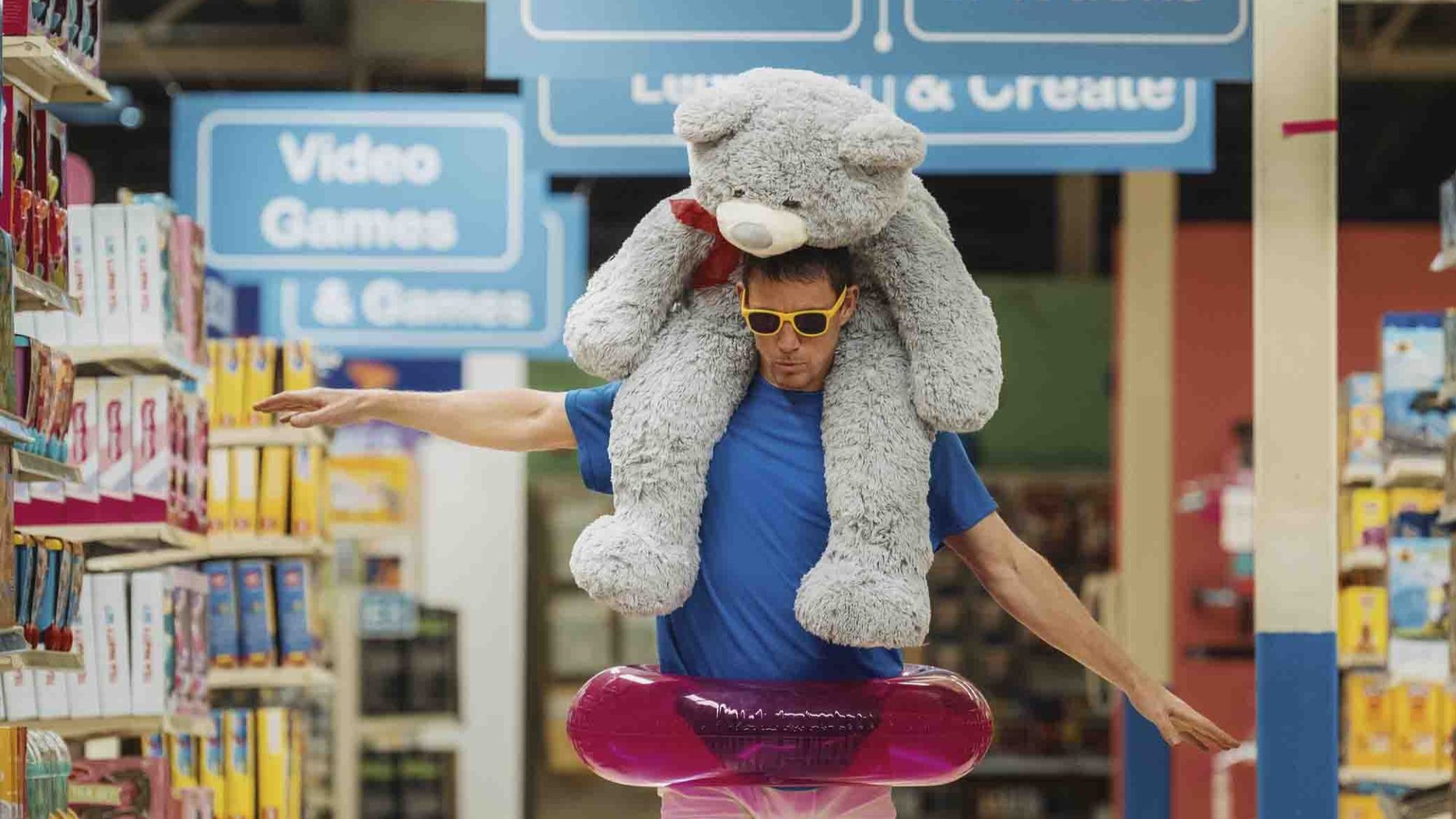 Channing Tatum wearing sunglasses and an inflatable tube with a stuffed bear on his shoulders in Roofman