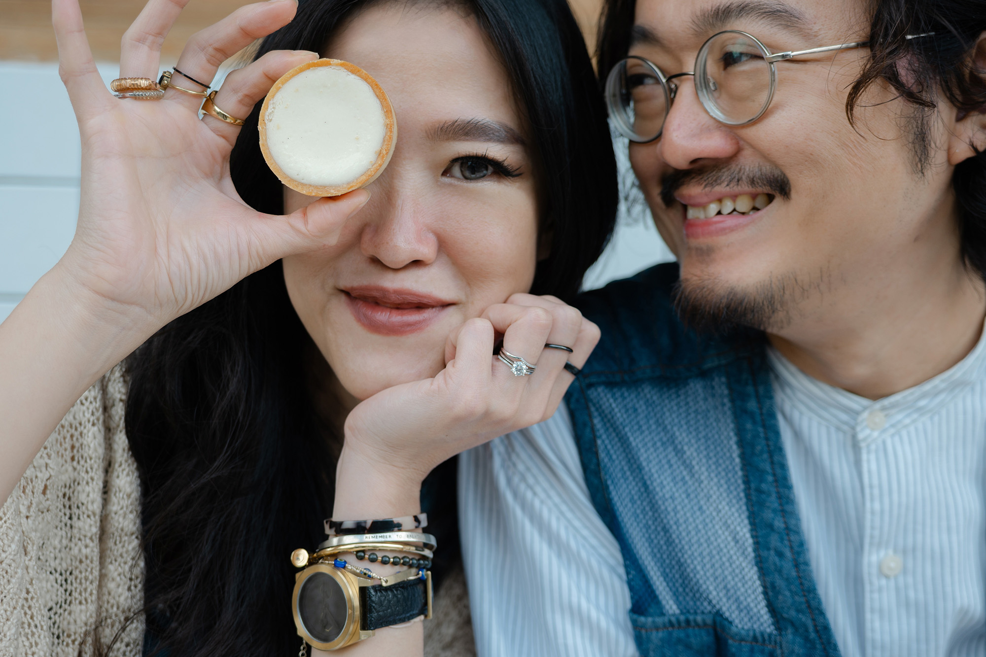 couple smile, one holds cake in front of face
